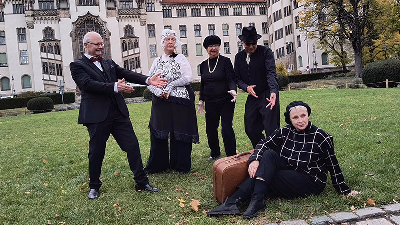 2026-05-LeseBuehne_Theatergruppe-ganz-dicht-dran Theatergruppe ganz dicht dran vor einem schlossähnlichen Gebäude